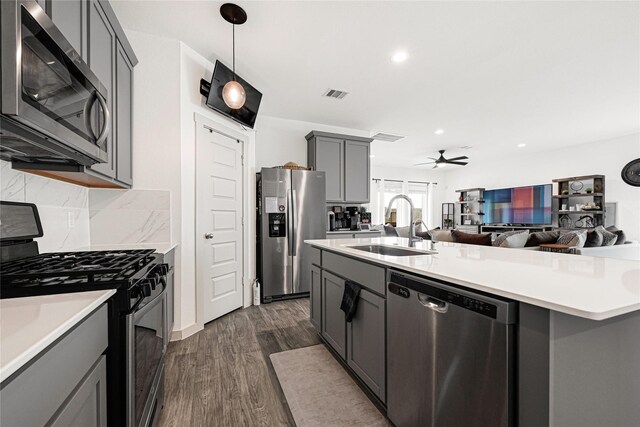 kitchen featuring a sink, stainless steel appliances, open floor plan, a ceiling fan, and gray cabinetry