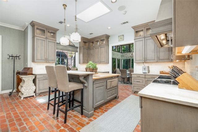 11519 Shadow Way St, Houston, TX 77024 - kitchen featuring tasteful backsplash, brick floor, a kitchen bar, gray cabinetry, and a warming drawer