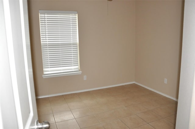 empty room featuring baseboards and light tile patterned flooring