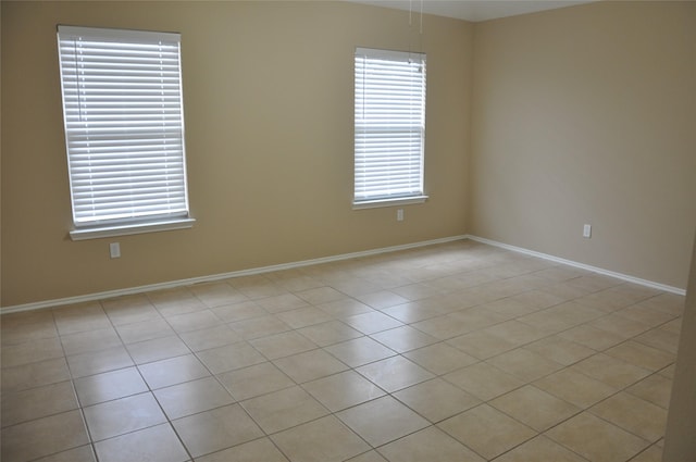 empty room with baseboards and light tile patterned floors
