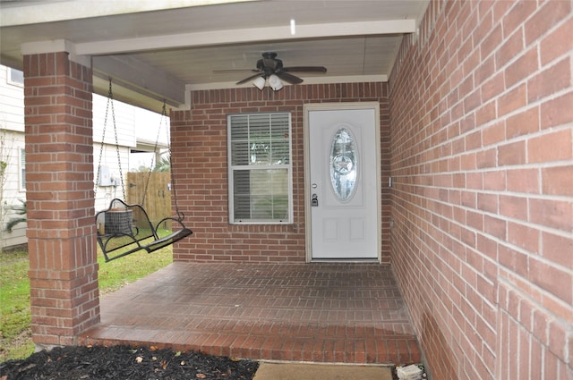 view of exterior entry featuring brick siding and ceiling fan