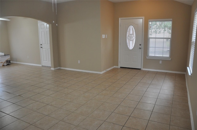 entryway featuring baseboards, light tile patterned floors, and arched walkways