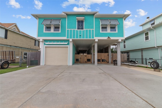 beach home with a garage, fence, a carport, and concrete driveway