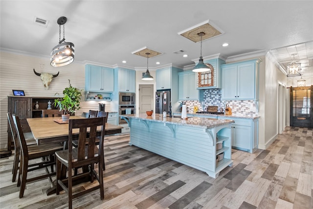 kitchen with decorative backsplash, blue cabinetry, a breakfast bar area, light stone counters, and appliances with stainless steel finishes