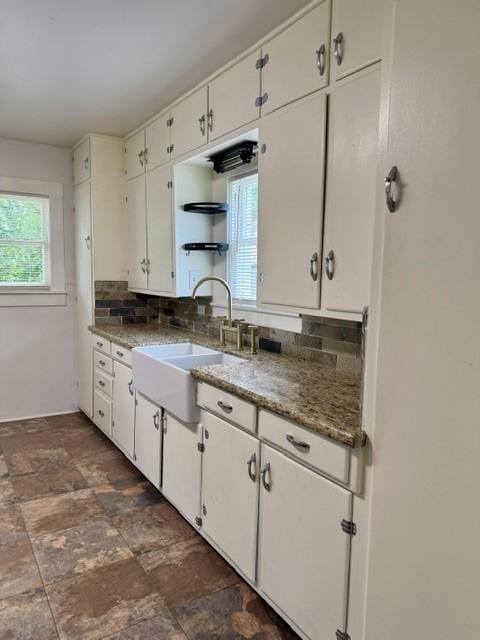 kitchen with a sink, white cabinetry, decorative backsplash, and plenty of natural light