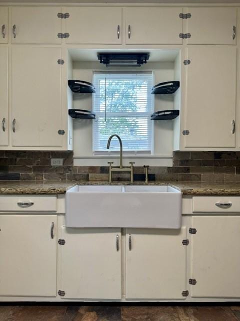 kitchen featuring dark stone countertops, a sink, white cabinets, and tasteful backsplash