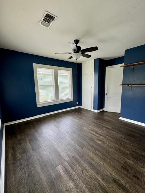 interior space with baseboards, visible vents, a ceiling fan, and dark wood-type flooring