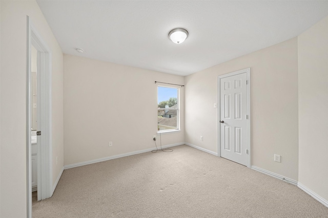 empty room with light colored carpet and baseboards