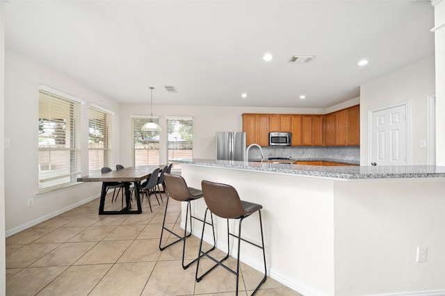 kitchen with baseboards, visible vents, stainless steel appliances, and brown cabinetry