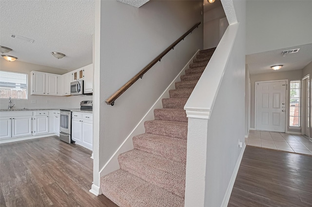 23931 Griffin House Ln, Katy, TX 77493 - stairway with wood finished floors, visible vents, baseboards, and a textured ceiling
