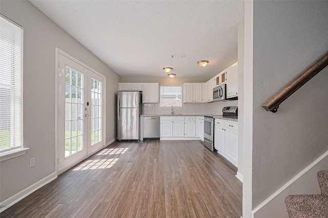 23931 Griffin House Ln, Katy, TX 77493 - kitchen featuring white cabinetry, visible vents, stainless steel appliances, and wood finished floors