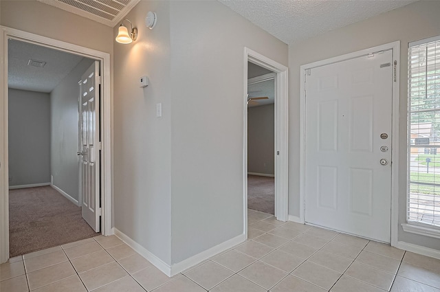 23931 Griffin House Ln, Katy, TX 77493 - entrance foyer featuring light tile patterned floors, visible vents, baseboards, a textured ceiling, and light colored carpet