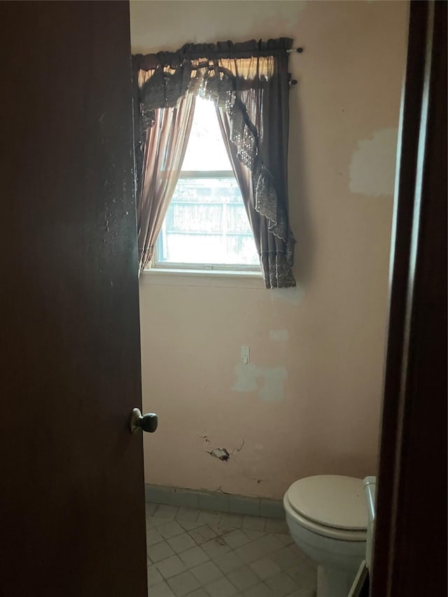 bathroom featuring baseboards, tile patterned floors, and toilet