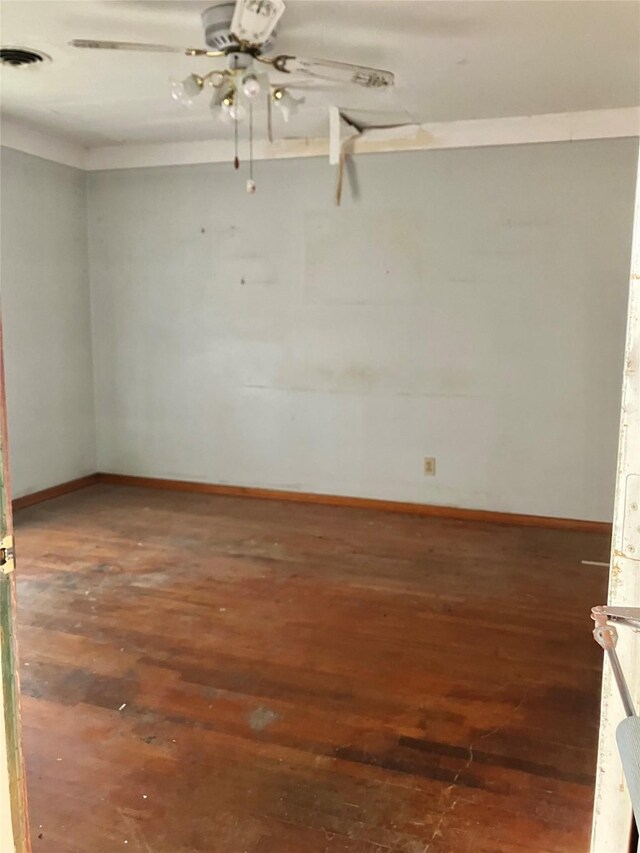 empty room with baseboards, visible vents, ceiling fan, and hardwood / wood-style flooring