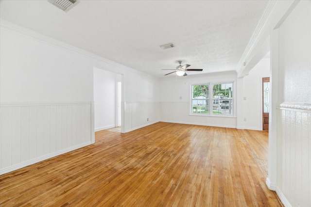 unfurnished room with light wood-style floors, crown molding, a ceiling fan, and visible vents