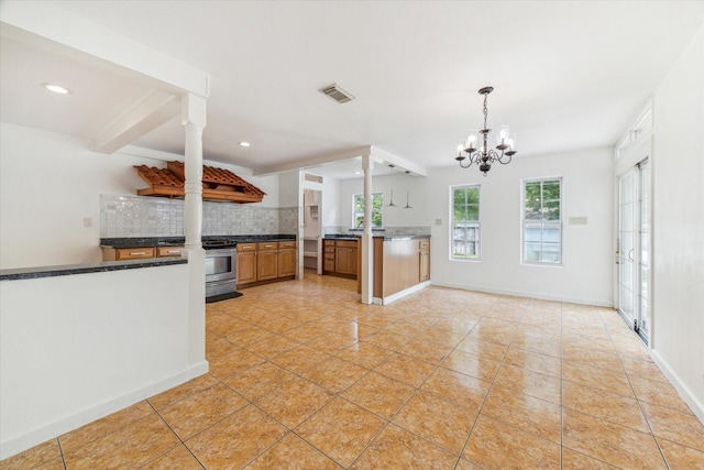kitchen featuring backsplash, visible vents, dark countertops, stainless steel range with gas cooktop, and an inviting chandelier