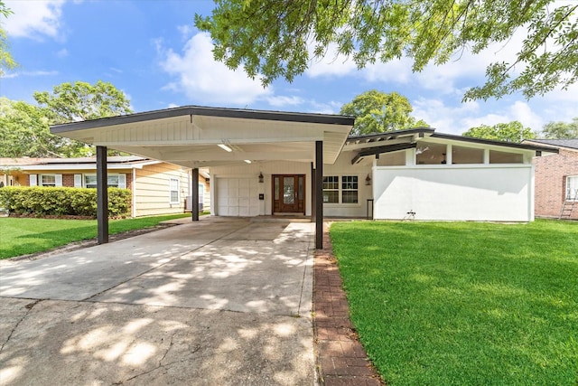 mid-century home featuring a carport, an attached garage, concrete driveway, and a front yard