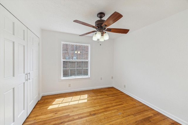 unfurnished bedroom with baseboards, light wood finished floors, ceiling fan, and a closet