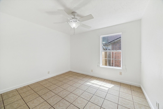 spare room featuring baseboards, ceiling fan, and light tile patterned floors