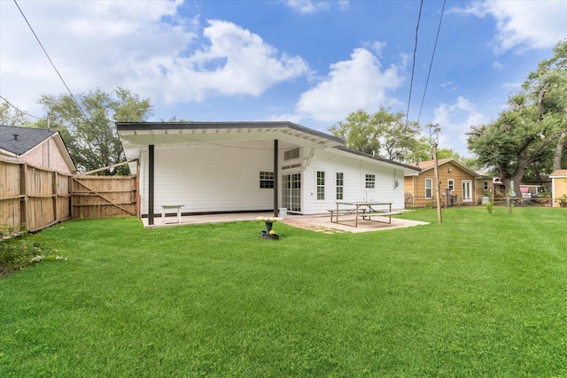 back of property featuring fence, a lawn, and a patio area