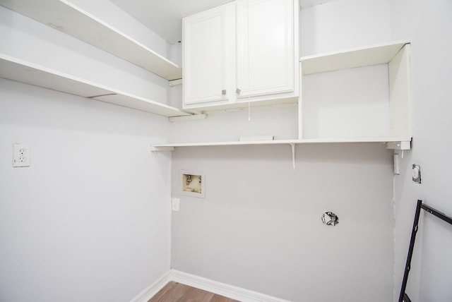 washroom featuring baseboards, hookup for a washing machine, wood finished floors, and cabinet space