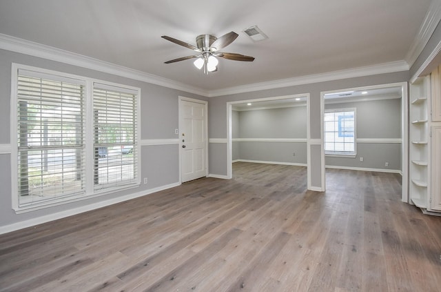 interior space with wood finished floors, a ceiling fan, ornamental molding, and baseboards