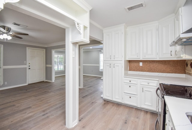 kitchen featuring visible vents, white cabinets, light wood-style flooring, and decorative backsplash