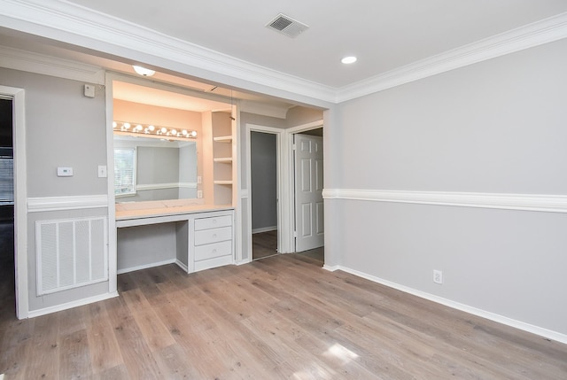 unfurnished bedroom featuring built in desk, crown molding, visible vents, and light wood-type flooring