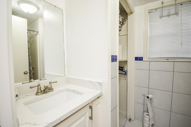 full bath with tile walls, walk in shower, and vanity