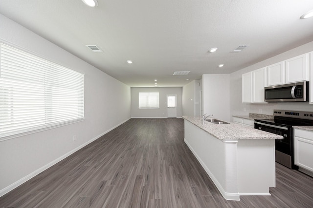 8113 Burnt Orchid Dr, Houston, TX 77016 - kitchen featuring stainless steel appliances, white cabinetry, dark wood-type flooring, and recessed lighting