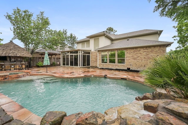 view of swimming pool featuring fence, outdoor dry bar, a sunroom, a patio area, and a pool with connected hot tub