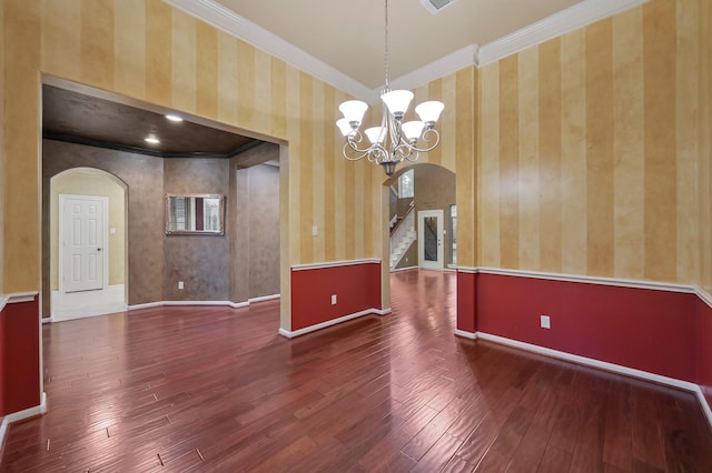 unfurnished room with crown molding, arched walkways, and hardwood / wood-style flooring