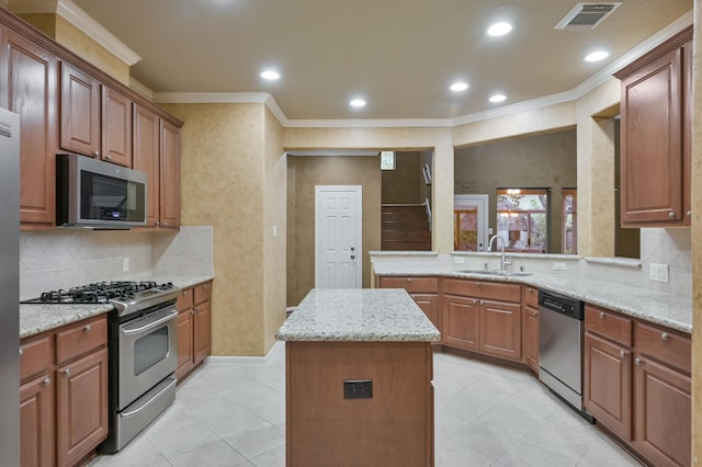 kitchen featuring a kitchen island, visible vents, crown molding, a sink, and stainless steel appliances
