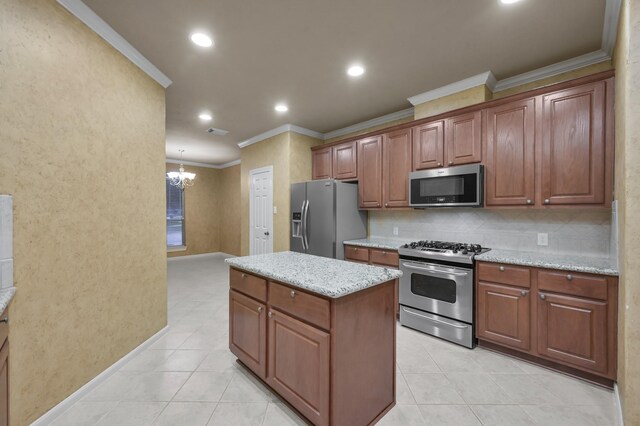 kitchen featuring ornamental molding, a kitchen island, light stone countertops, a chandelier, and appliances with stainless steel finishes