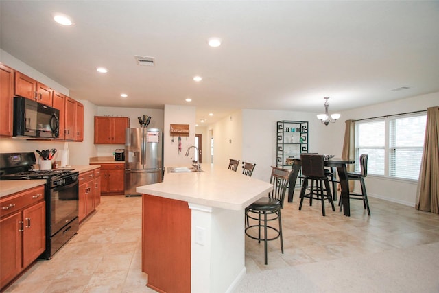 kitchen featuring a breakfast bar area, light countertops, brown cabinets, a sink, and black appliances