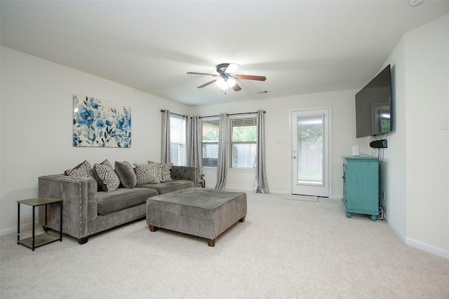 living room featuring baseboards, ceiling fan, visible vents, and light colored carpet