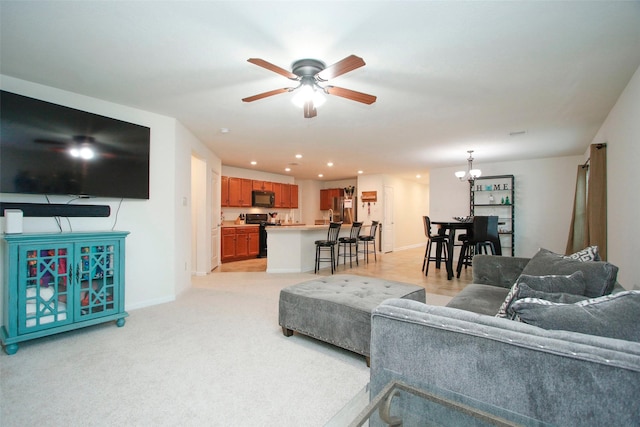 living area with baseboards, recessed lighting, ceiling fan with notable chandelier, and light carpet