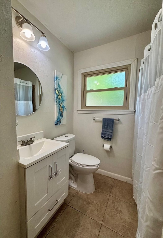 bathroom with vanity, tile patterned floors, toilet, baseboards, and a textured ceiling