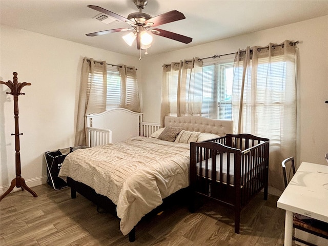 bedroom with baseboards, visible vents, wood finished floors, and ceiling fan