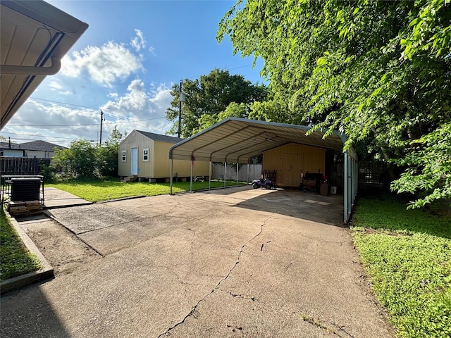 view of vehicle parking featuring a storage unit, fence, a carport, and driveway