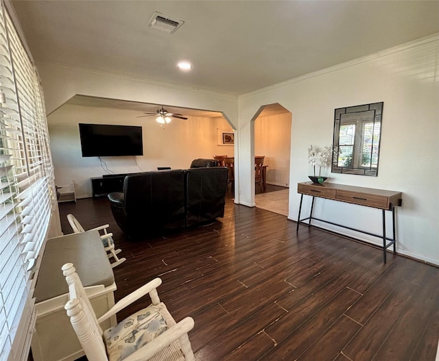 living area with crown molding, visible vents, arched walkways, wood finished floors, and a ceiling fan