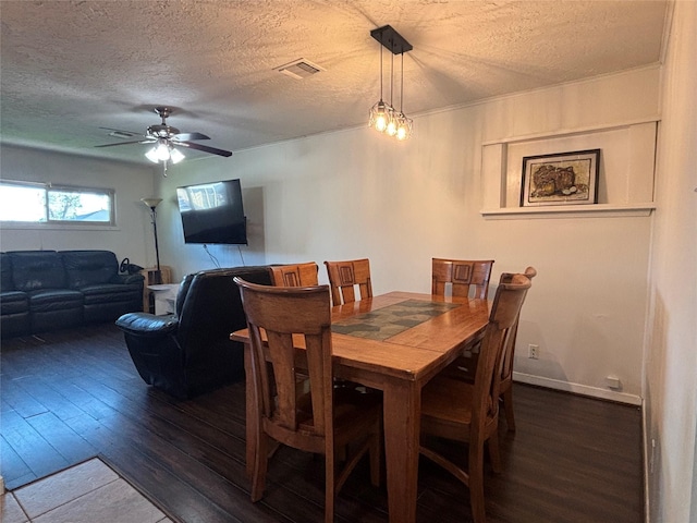 dining room featuring visible vents, hardwood / wood-style flooring, a ceiling fan, and a textured ceiling