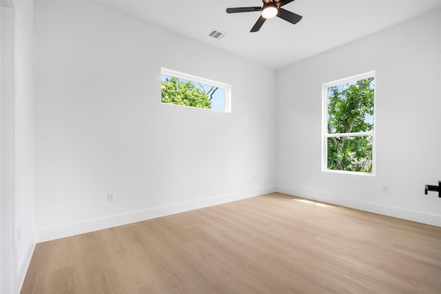 empty room featuring visible vents, a ceiling fan, a healthy amount of sunlight, and light wood-style flooring