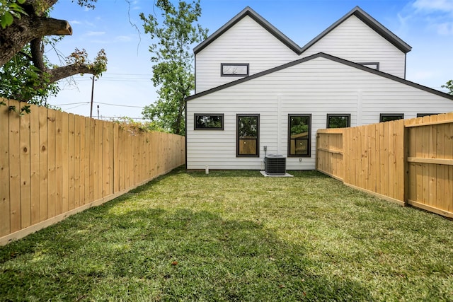 rear view of property with cooling unit, a yard, and a fenced backyard