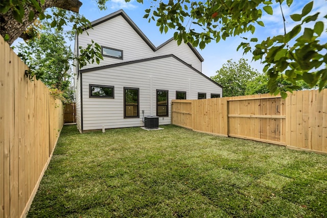 back of property with a fenced backyard, a yard, and central air condition unit