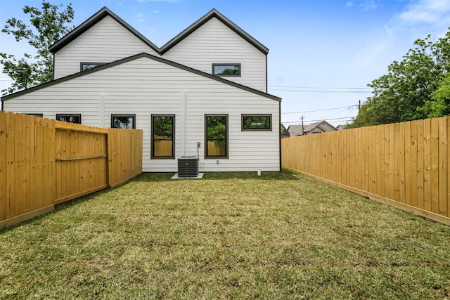 rear view of house with a lawn, a fenced backyard, and central AC unit