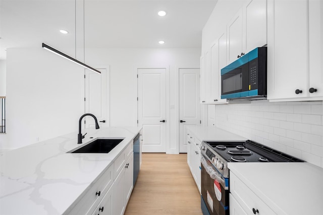 kitchen featuring recessed lighting, a sink, decorative backsplash, white cabinets, and appliances with stainless steel finishes