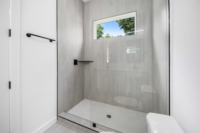 full bath with baseboards, toilet, a tile shower, and tile patterned flooring