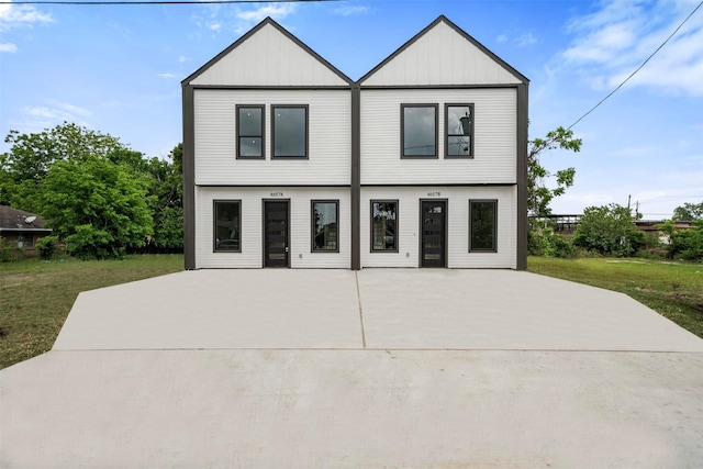 view of front of home featuring a patio area, a front yard, and board and batten siding