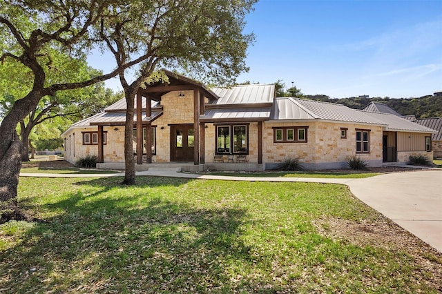 view of front of house with a front yard, a standing seam roof, metal roof, and stone siding
